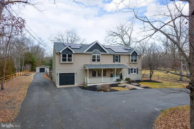 a front view of a house with swimming pool and a yard with trees