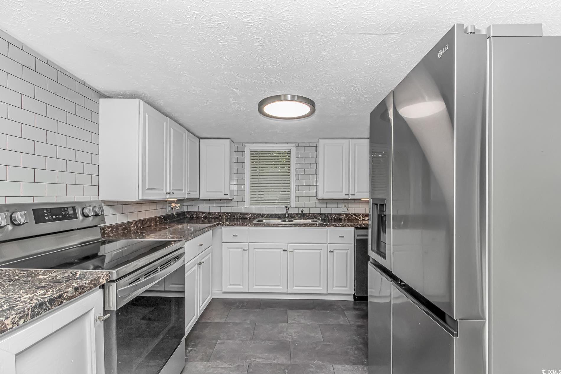 159 Offshore Drive Murrells Inlet, SC 29576 - Photo 8 of 35 Kitchen with appliances with stainless steel finishes, a sink, white cabinets, backsplash, and a textured ceiling