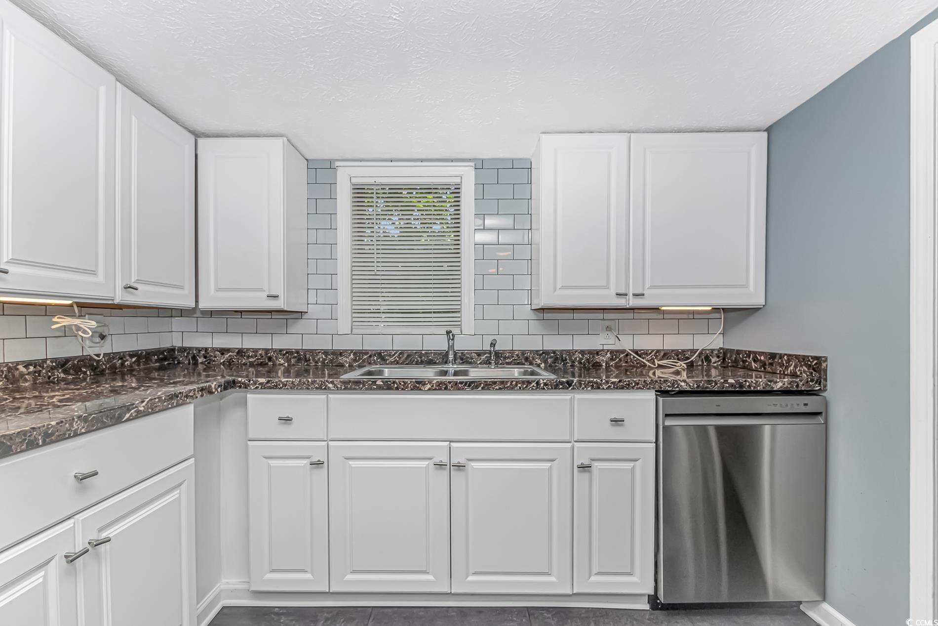 159 Offshore Drive Murrells Inlet, SC 29576 - Photo 9 of 35 Kitchen featuring stainless steel dishwasher, a sink, white cabinetry, backsplash, and a textured ceiling