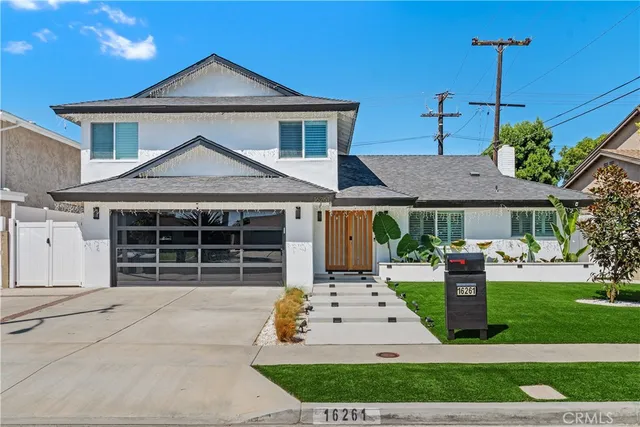 a front view of a house with a yard and potted plants