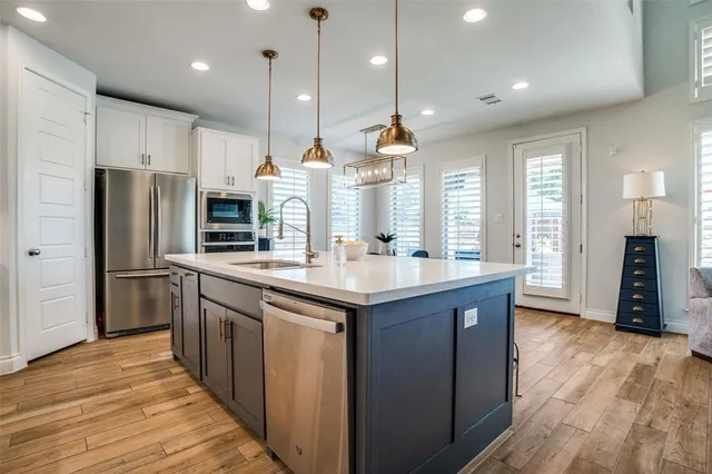 a kitchen with stainless steel appliances granite countertop a sink a stove and a wooden floor
