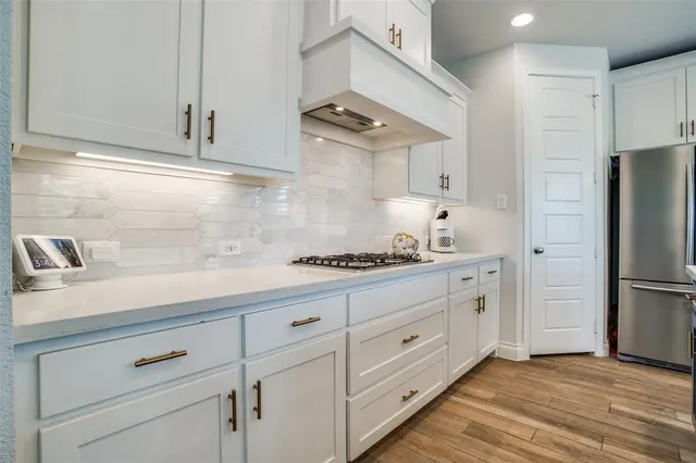 a kitchen with granite countertop white cabinets and refrigerator