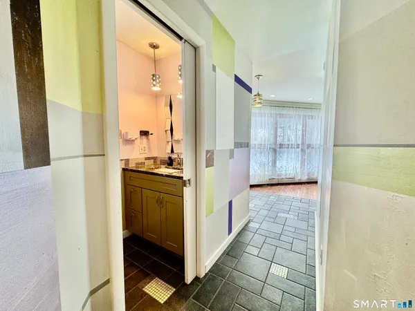 a view of a hallway with wooden floor and a bathroom
