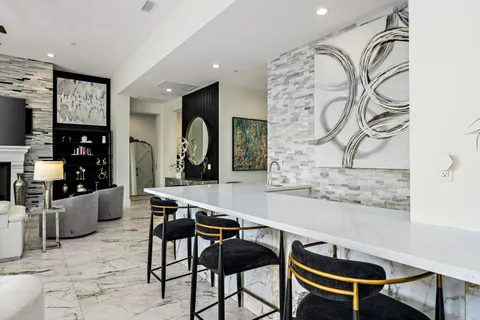 a view of a patio with table and chairs potted plants and floor to ceiling window