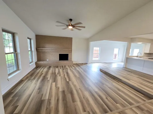 a view of empty room with wooden floor and fan