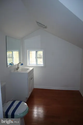 a bathroom with a toilet a sink a mirror and a window