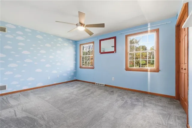 an empty room with windows and fan