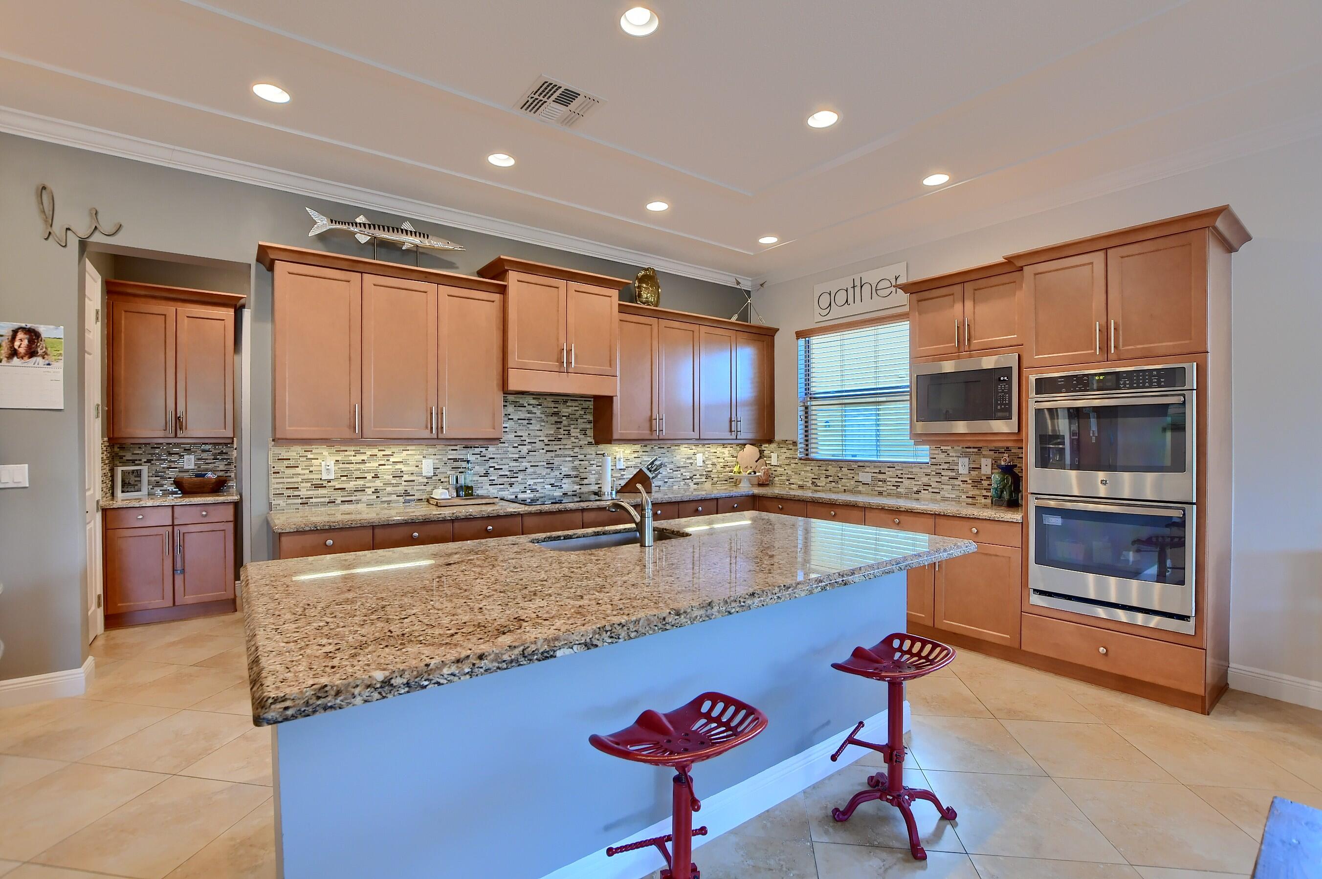 12161 Boca Reserve Lane Boca Raton, FL 33428 - Photo 30 of 53 a large kitchen with kitchen island a large counter top space a sink stainless steel appliances and cabinets
