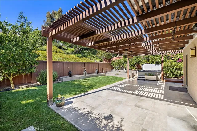 a view of a patio with table and chairs under an umbrella with a small yard