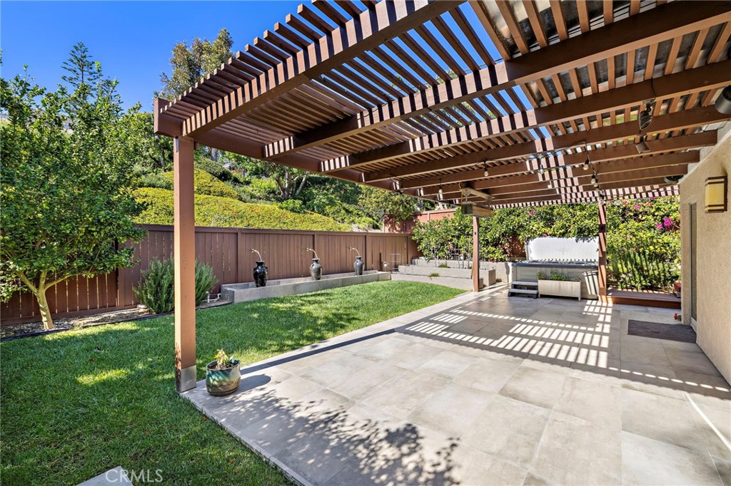 a view of a patio with table and chairs under an umbrella with a small yard