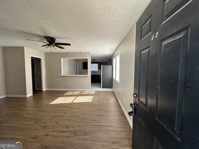 a view of a hallway with wooden floor and a ceiling fan