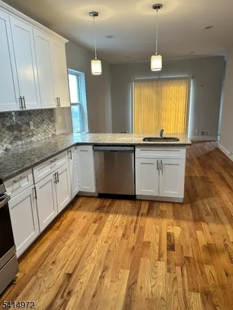 a large kitchen with granite countertop a sink window and cabinets
