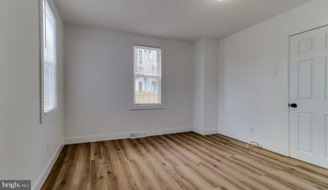 a view of a bedroom with wooden floor and window