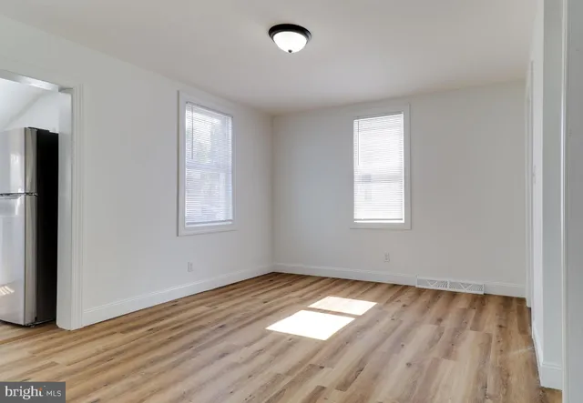 a living room with stainless steel appliances kitchen island a sink wooden floor and hallway view
