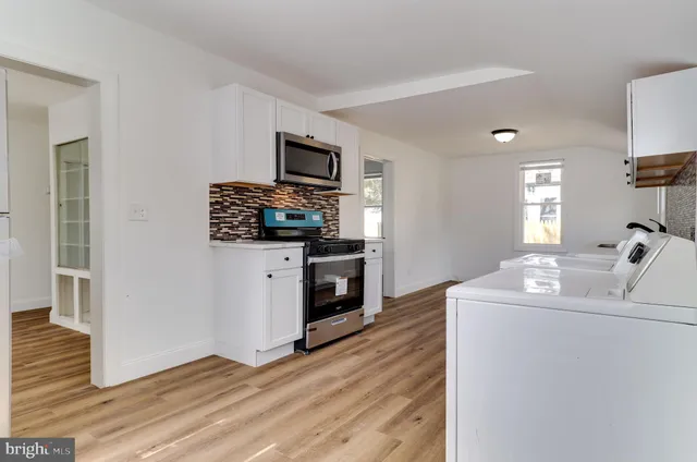 a open kitchen with white cabinets and wooden floor