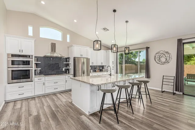 a kitchen with stainless steel appliances kitchen island granite countertop a stove a sink and a refrigerator