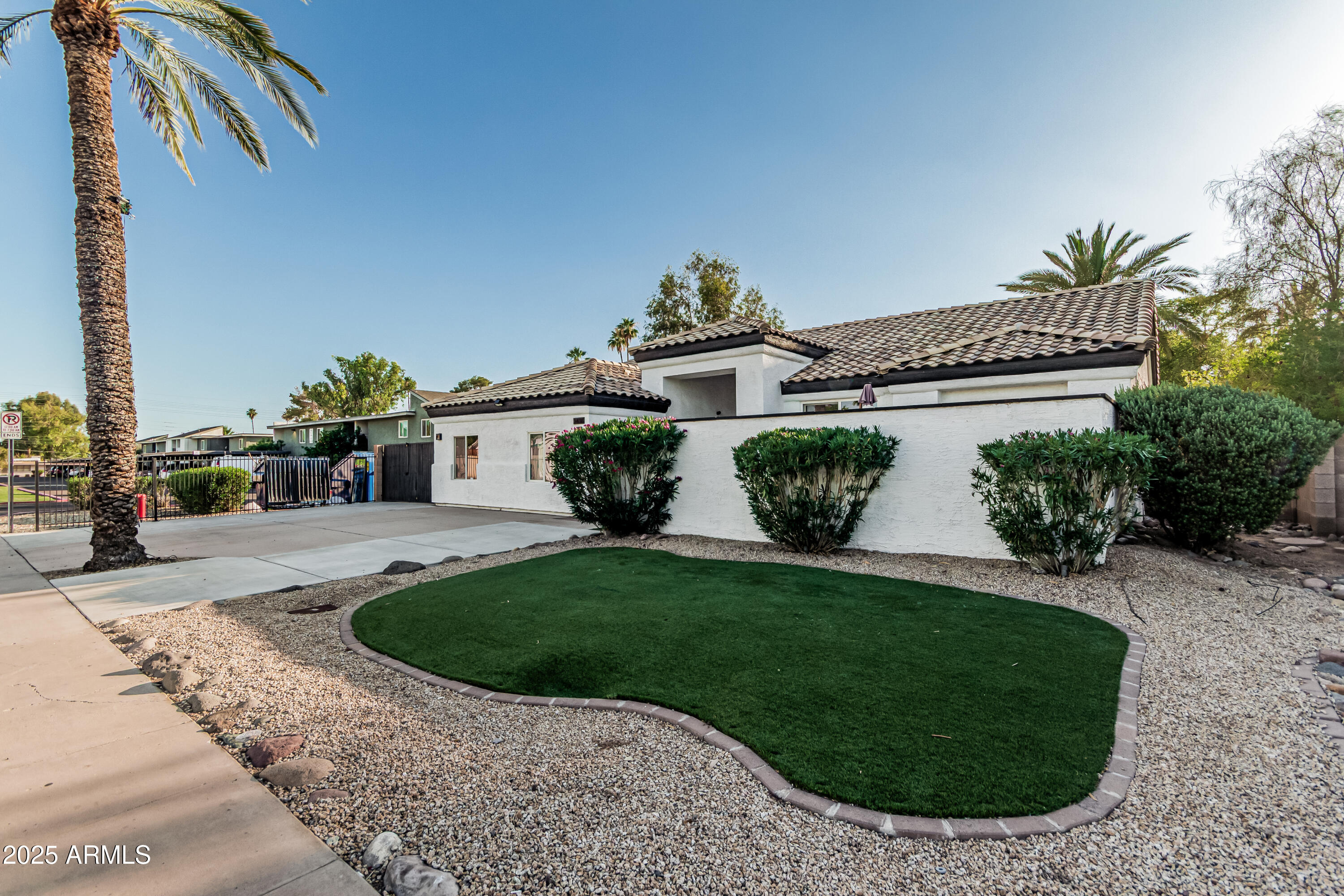 a view of a white house with a big yard and potted plants