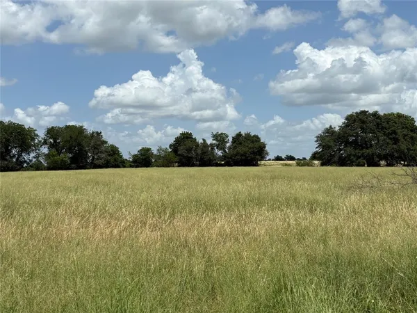 a view of a green field with wooden fence