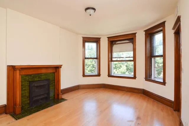 an empty room with windows and fireplace