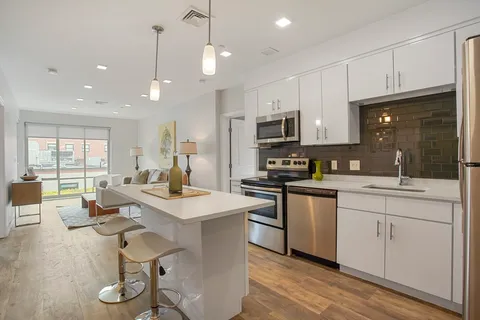 a open kitchen with stainless steel appliances kitchen island granite countertop a sink dishwasher a stove a refrigerator and a dining table with wooden floor