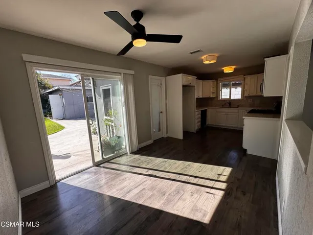 a living room with stainless steel appliances granite countertop furniture wooden floor and a large window