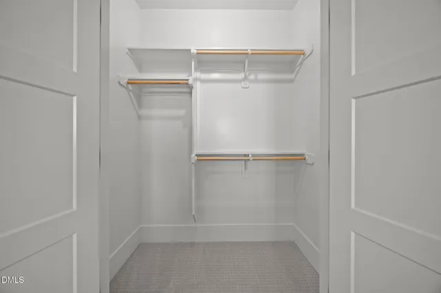 a view of an empty room with a window and a kitchen