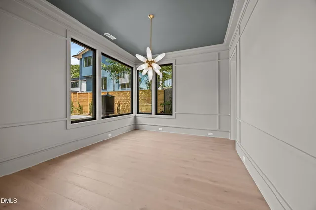 a view of an empty room with window and chandelier