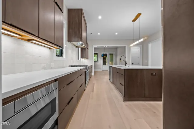 a large kitchen with a large counter top stainless steel appliances and cabinets