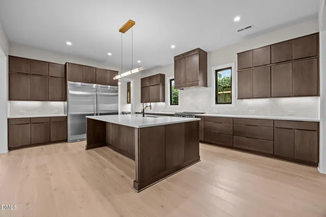 a living room with stainless steel appliances furniture a chandelier and a wooden floor