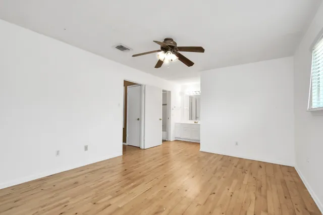 a view of empty room with wooden floor and fan