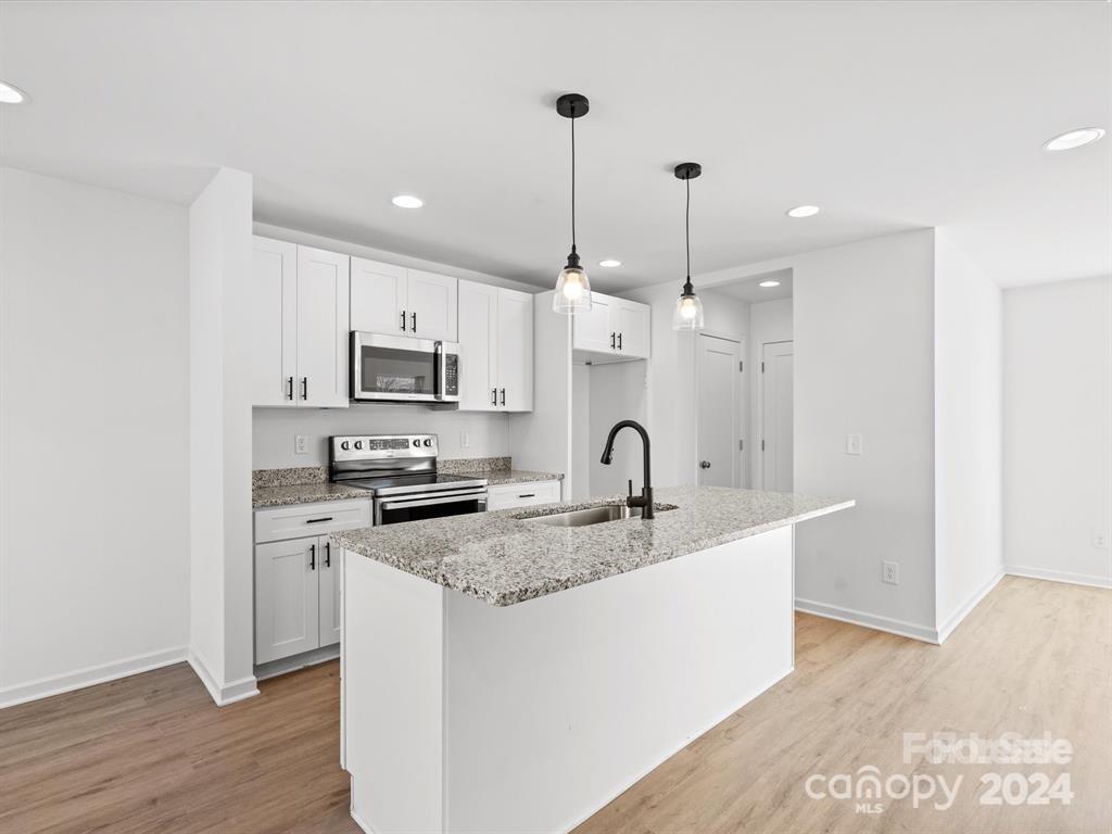 3799 Herman Sipe Road, Unit B Conover, NC 28613 - Photo 30 of 44 a kitchen with stainless steel appliances granite countertop a sink a stove a refrigerator and white cabinets with wooden floor