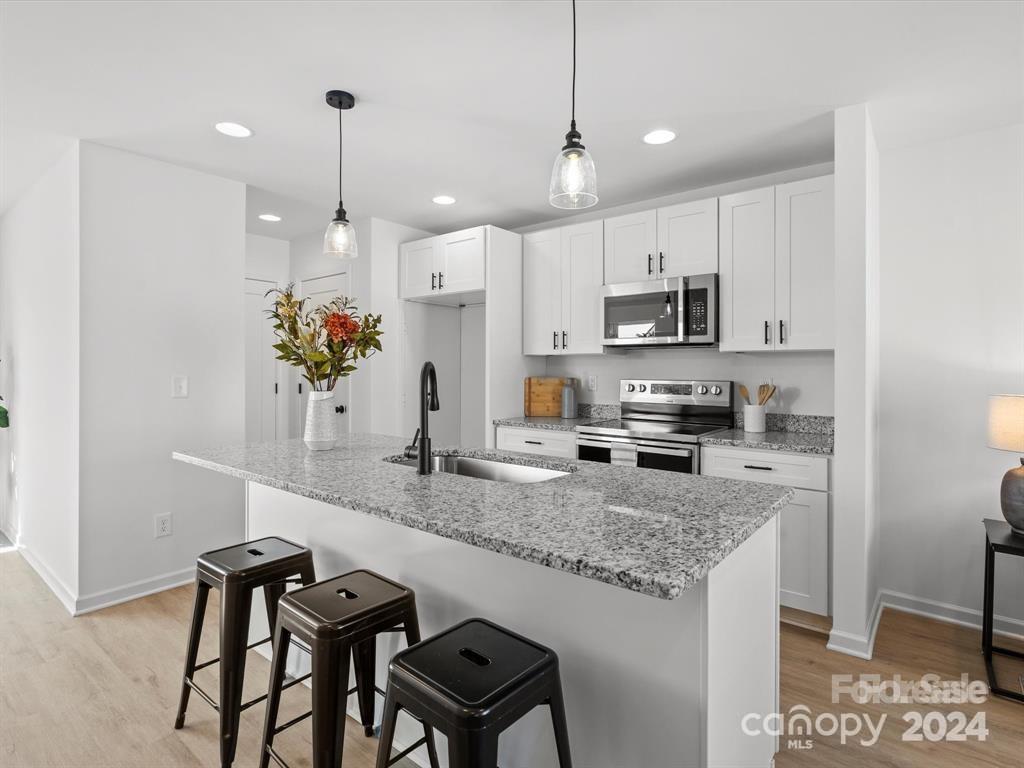 3799 Herman Sipe Road, Unit B Conover, NC 28613 - Photo 10 of 44 a kitchen with kitchen island granite countertop a table chairs microwave and cabinets