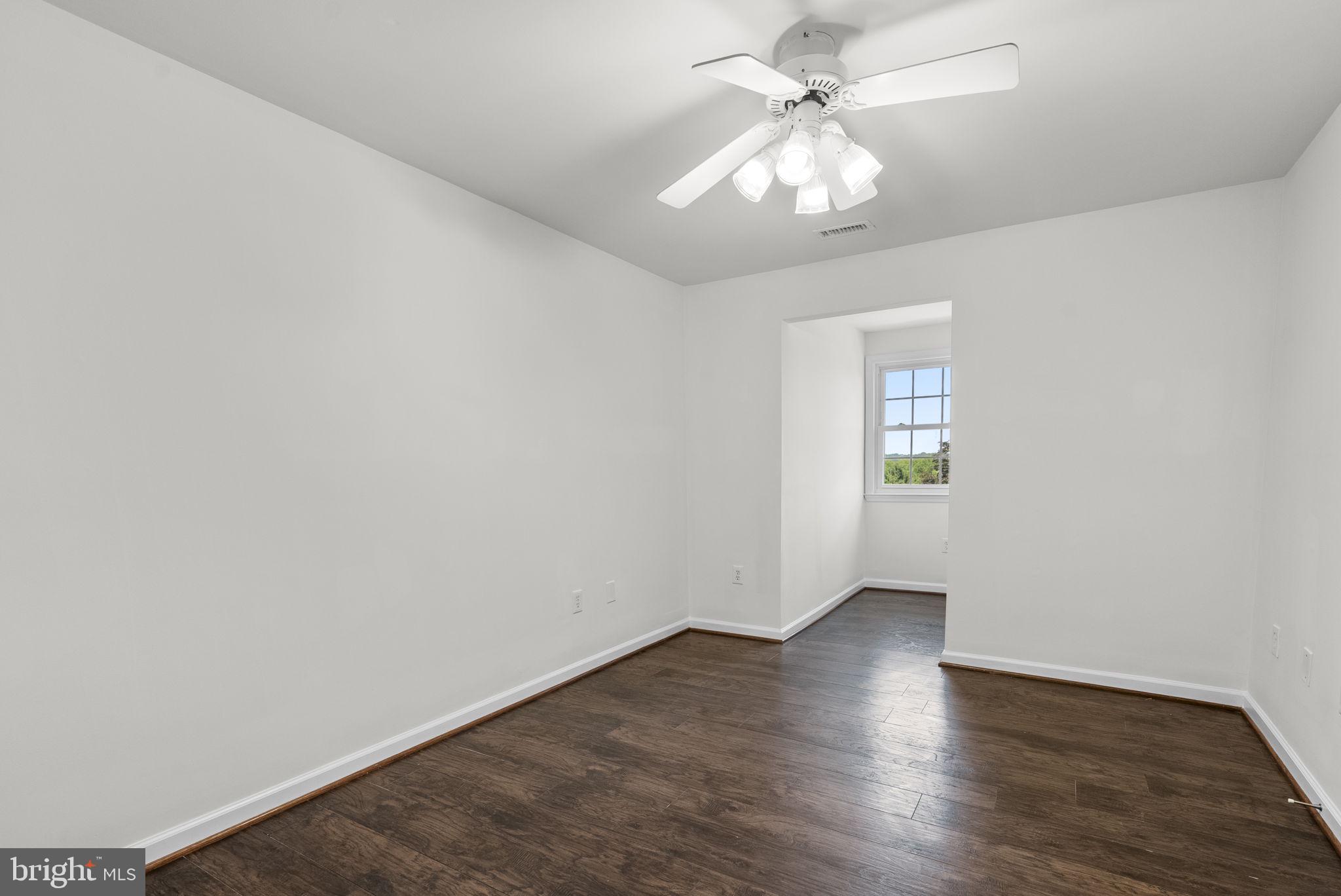 24000 Clarksburg Road Clarksburg, MD 20871 - Photo 32 of 60 an empty room with wooden floor chandelier fan and windows