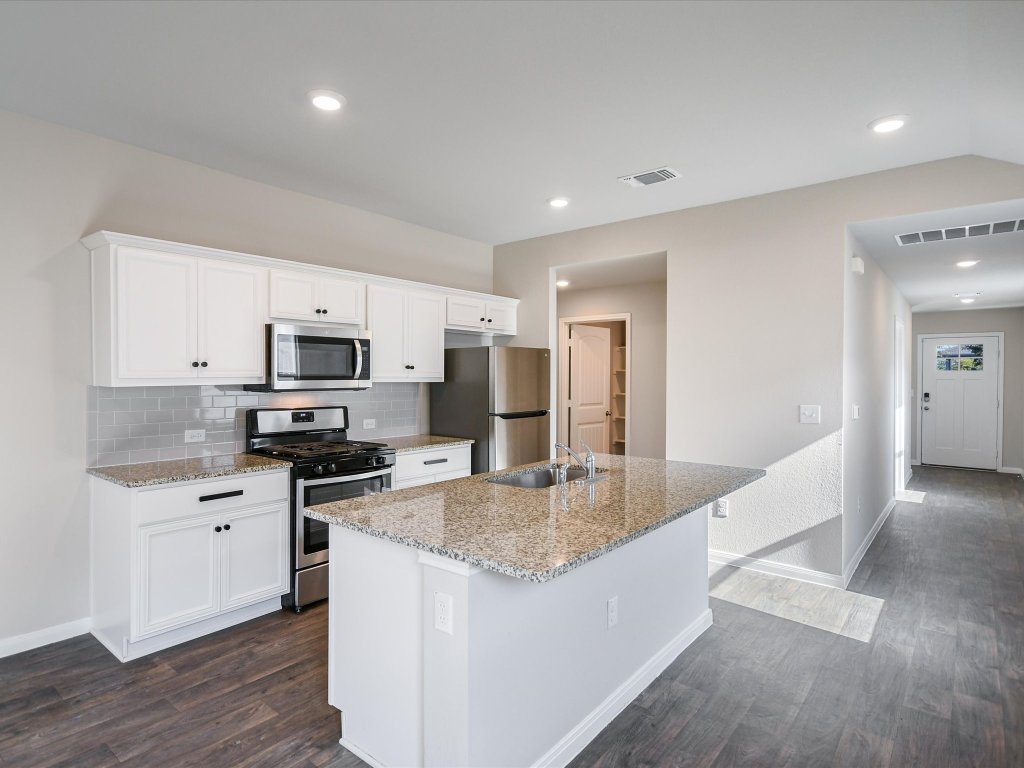 14408 Boquist Drive Pflugerville, TX 78660 - Photo 3 of 20 a kitchen with stainless steel appliances granite countertop a sink a stove top oven a counter space and cabinets
