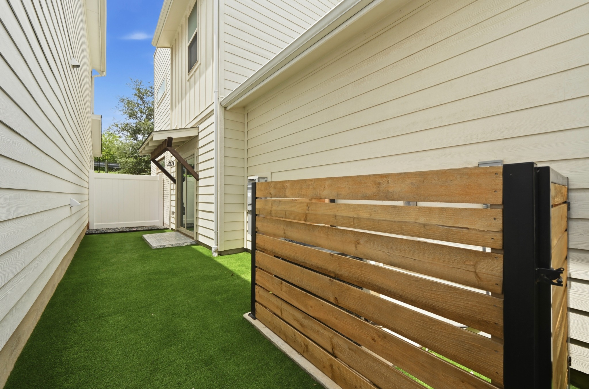 8201 Frida Bend Austin, TX 78744 - Photo 25 of 29 A well-maintained side yard features vibrant artificial turf and a private wooden fence.
