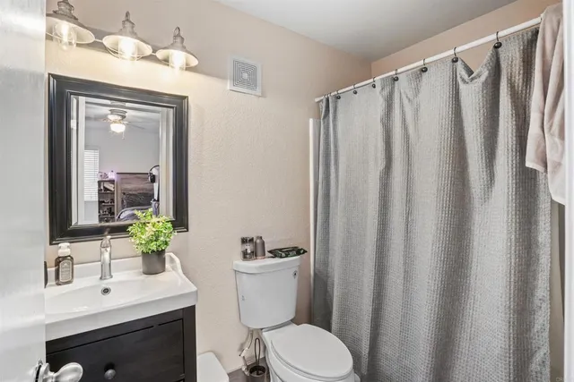a bathroom with a sink a toilet a mirror and shower curtain