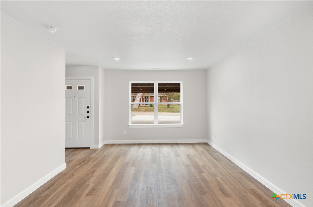 905 Martin Luther King Jr Lane, Unit B Temple, TX 76504 - Photo 4 of 24 an empty room with wooden floor and windows