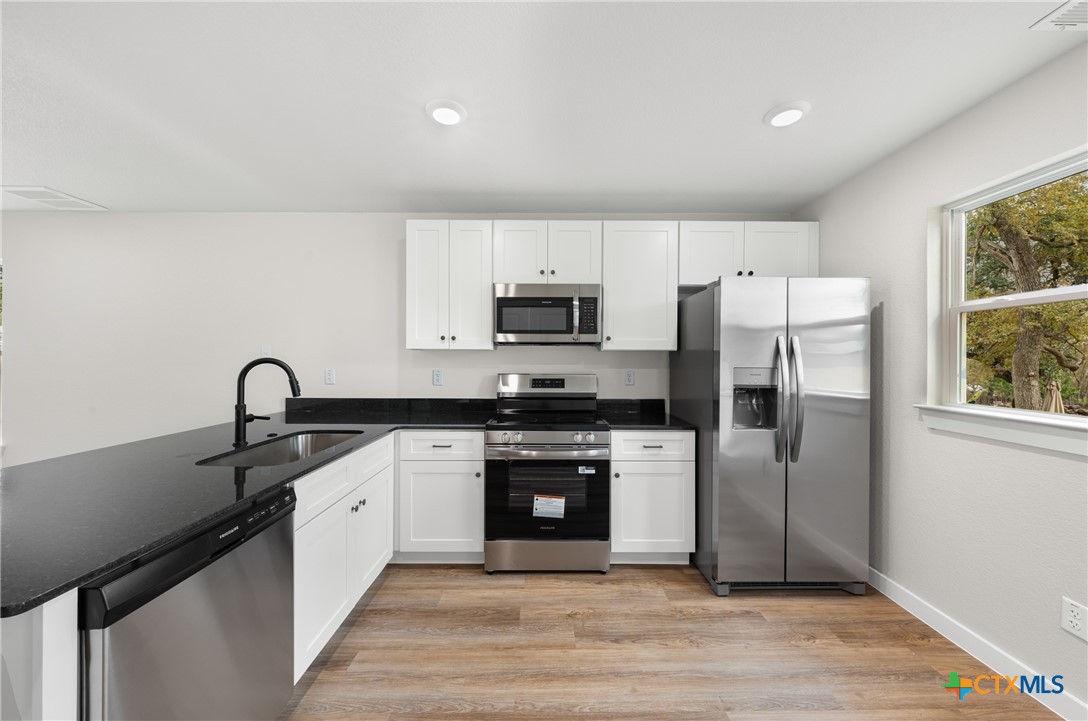 905 Martin Luther King Jr Lane, Unit B Temple, TX 76504 - Photo 9 of 24 a kitchen with stainless steel appliances granite countertop a stove a sink and a refrigerator