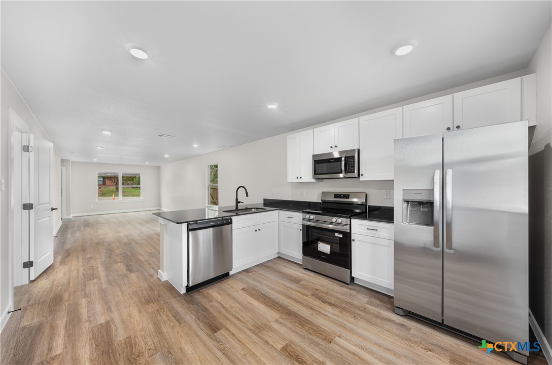905 Martin Luther King Jr Lane, Unit B Temple, TX 76504 - Photo 10 of 24 a kitchen with granite countertop a refrigerator stove top oven and sink