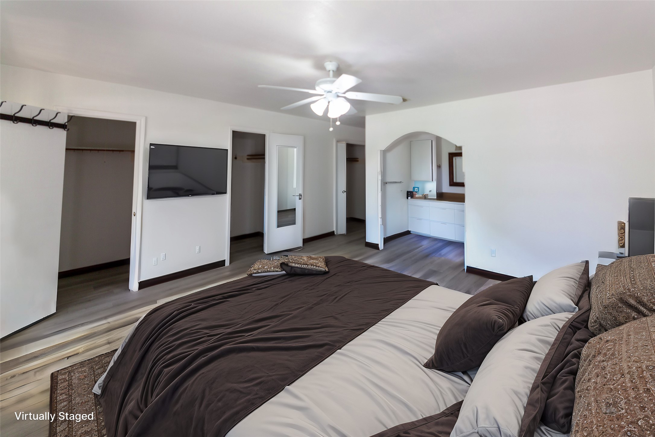 8826 Roos Road Houston, TX 77036 - Photo 14 of 42 This spacious bedroom features a neutral color palette, and a ceiling fan. It includes dual closets and an archway leading to a vanity area, offering both comfort and functionality.