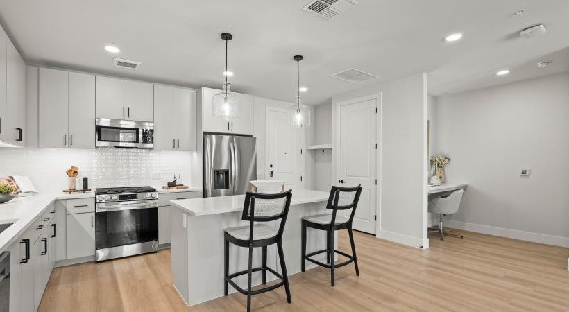 500 East Rivulon Boulevard, Unit C1 Gilbert, AZ 85297 - Photo 10 of 33 a kitchen with stainless steel appliances a stove a sink dishwasher a refrigerator and white cabinets with wooden floor