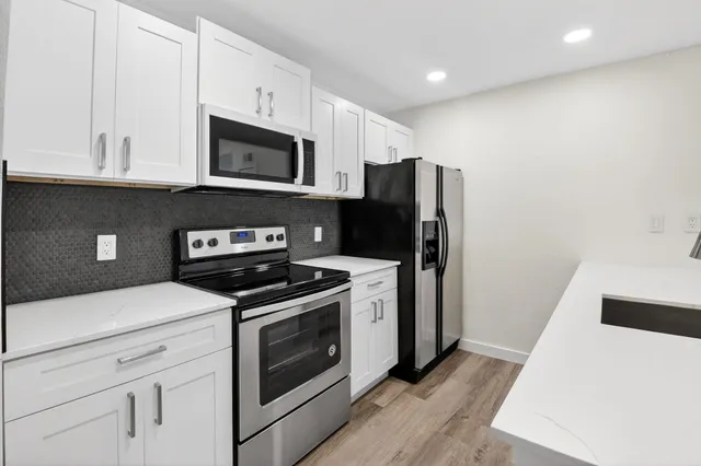 a kitchen with stainless steel appliances white cabinets and wooden floor