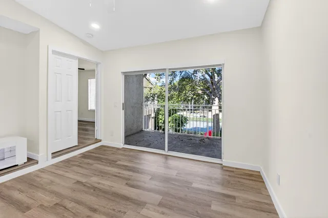 a view of empty room with wooden floor and fan