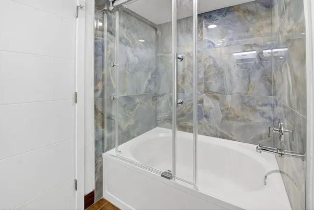 a white bath tub sitting next to a shower
