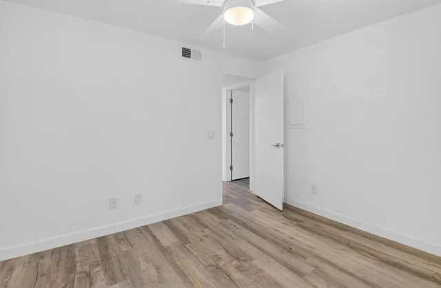 an empty room with wooden floor and fan