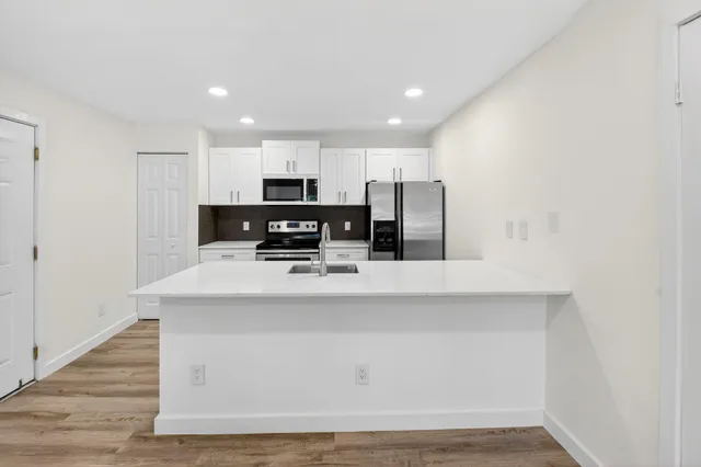 a kitchen with a refrigerator and white cabinets