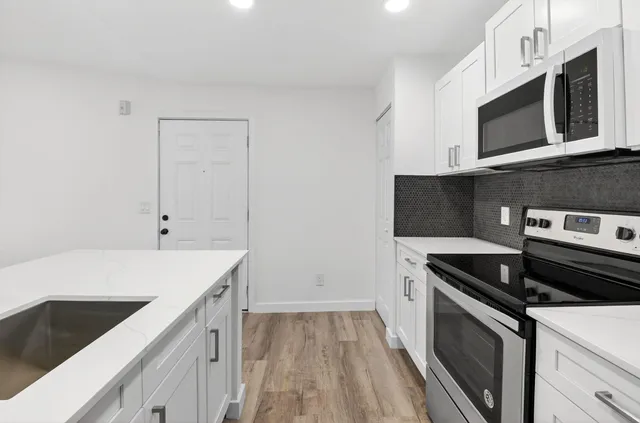 a kitchen with stainless steel appliances a stove microwave and sink