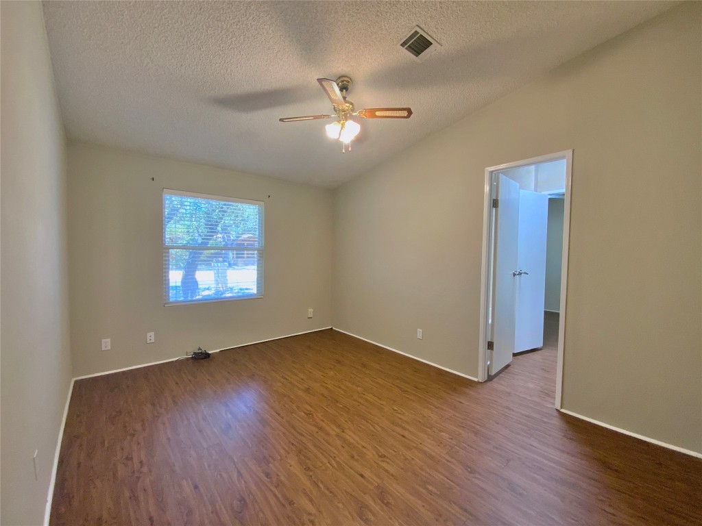 1301 Lipan Trail Austin, TX 78733 - Photo 12 of 39 Empty room with dark wood-type flooring, a textured ceiling, a ceiling fan, and lofted ceiling