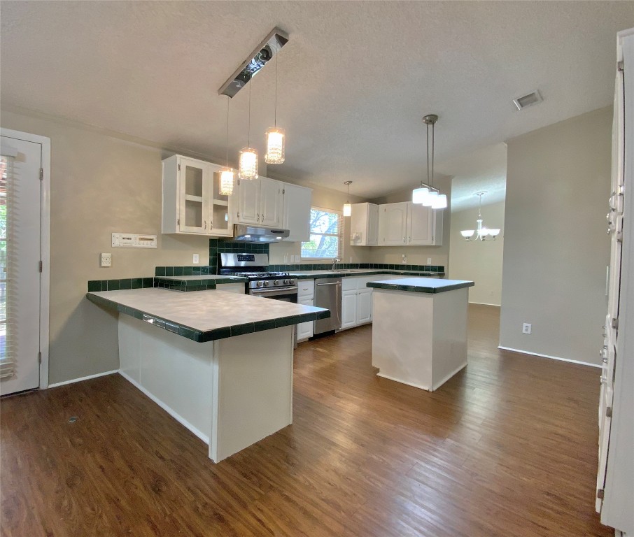 1301 Lipan Trail Austin, TX 78733 - Photo 21 of 39 Kitchen with white cabinets, pendant lighting, stainless steel appliances, a peninsula, and dark wood finished floors