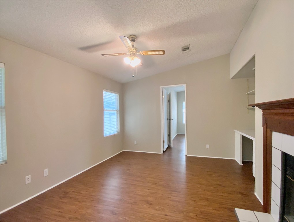 1301 Lipan Trail Austin, TX 78733 - Photo 3 of 39 Unfurnished living room featuring a fireplace, dark wood-style floors, a textured ceiling, and ceiling fan